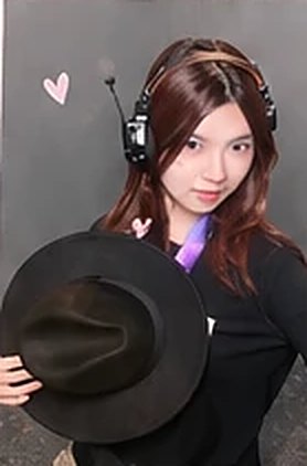 Beaker holding a black hat and wearing a headset